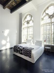 a white bedroom with a large bed and two windows at THE QVEST hideaway in Cologne