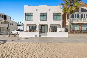 a white house with a palm tree on the beach at 1628 West Oceanfront Oasis 6 in Newport Beach +11 photos
