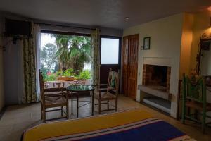 1 dormitorio con mesa, sillas y chimenea en Hotel Villas Paraiso, en Valle de Bravo