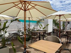 an outdoor patio with tables and chairs and umbrellas at La Boutique Puerta Osario in Córdoba