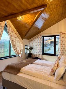 a bedroom with a large bed with large windows at Hanul Doctorului Badeni-Runcu Apartament in Bădeni