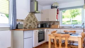 eine Küche mit weißen Schränken und einem Holztisch in der Unterkunft Ta Mill Cottages & Lodges - Meadowview Chalet 2 in Launceston