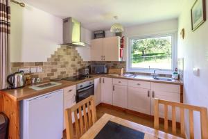 eine Küche mit weißen Schränken und einem Fenster in der Unterkunft Ta Mill Cottages & Lodges - Meadowview Chalet 2 in Launceston