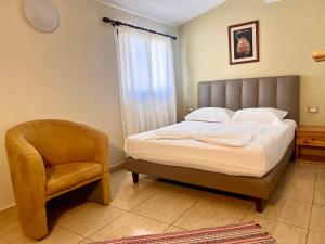a bedroom with a bed and a chair at Chalet Ambel in Dhërmi