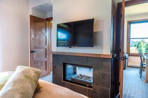 a living room with a fireplace with a flat screen tv above it at Lakefront, Mountain View - 2 Bedrooms Resort Suite in Lac-Superieur