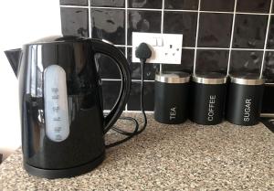 a black coffee pot on a counter with three cups at Cliftonville Apartments in Belfast