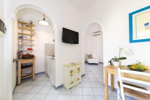 sala de estar con mesa y TV en la pared en Casa Margherita Ischia, en Isquia