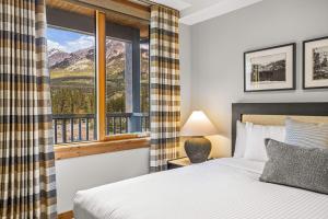 a bedroom with a bed and a window with a mountain view at Spring Creek Vacations in Canmore