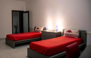 a room with two beds with red sheets and a mirror at Villa Balluta in St Julian's