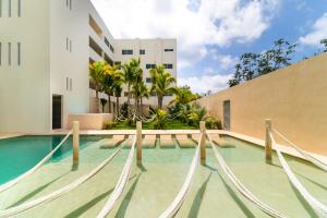 普拉亚卡门Penthouse with Jungle View Terrace Gym Pool HotTub的大楼前带吊床的游泳池