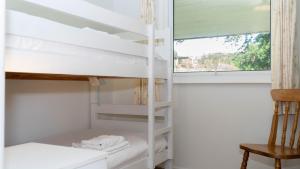 Zimmer mit Etagenbetten, einem Fenster und einem Stuhl in der Unterkunft Ta Mill Cottages & Lodges - Meadowview Chalet 4 in Launceston