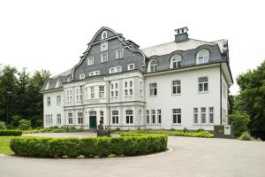 un grand bâtiment blanc avec un toit gris dans l'établissement Seminar- & Tagungshotel Große Ledder, à Wermelskirchen