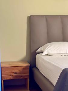 a bed with a wooden nightstand next to a white bed at Chalet Ambel in Dhërmi