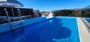 a blue swimming pool with a ladder and an umbrella at Vila Biser Vodice in Vodice