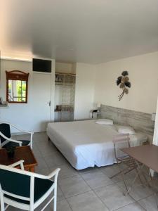 a bedroom with a bed and a table and chairs at Appartement à la marina Résidence HÔTEL VILLAGE SOLEIL Le Gosier in Le Gosier +4 photos