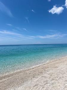 a beach with the ocean and a blue sky at Chalet Ambel in Dhërmi