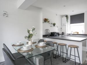 a kitchen with a glass table and chairs and a sink at Bodafon View in Llandudno