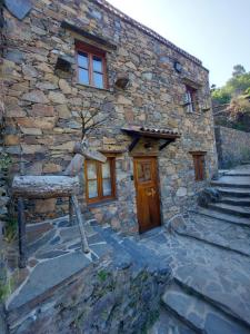 a stone building with a wooden door and stairs at Cantinho do Talasnal in Talasnal
