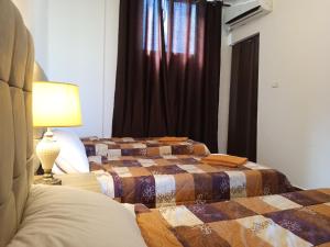 two beds in a bedroom with a lamp and a window at Petra Planet in Wadi Musa