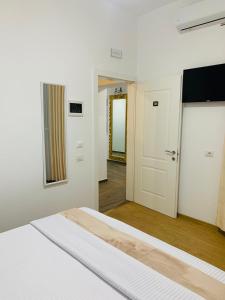 a white bedroom with a bed and a hallway at Vila Franko in Berat