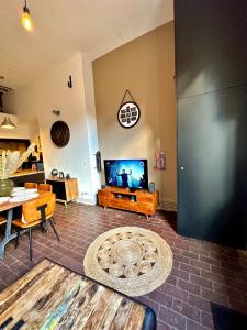 a living room with a flat screen tv and a table at Le Loft Rouen Centre in Rouen