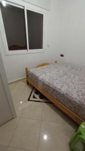 a bed in a room with two windows at Apartment 20m from Martil beach in Tétouan