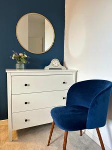 a blue chair next to a dresser with a mirror at Cosy flat in Alnwick in Alnwick