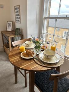 a wooden table with plates of food and orange juice at Cosy flat in Alnwick in Alnwick +12 photos