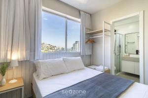 a bedroom with a bed and a large window at EVAs - Apartamentos charmosos com vista mar em Floripa in Florianópolis