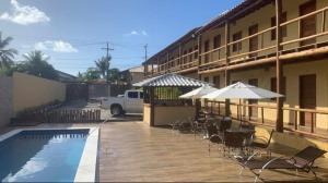 a pool with chairs and umbrellas next to a building at Pousada Ilha de Itacimirim in Camacari +6 photos
