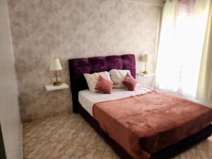 a bedroom with a bed with a purple headboard at Jolie appartement in Kenitra