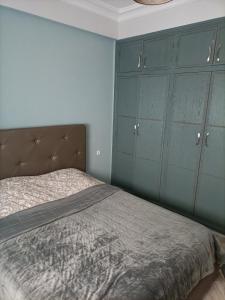 a bedroom with a bed with blue cabinets at Jolie appartement in Kenitra