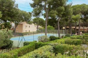 Una cancha de tenis rodeada de árboles y arbustos. en L'Intimate Sahara - Piscine - Tennis - Clim, en Cap d'Agde