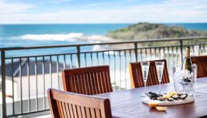 a table with a bottle of wine and glasses on the beach at The Palms Yamba - Overlooking Convent Beach in Yamba