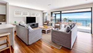 a living room with two couches and a television at The Palms Yamba - Overlooking Convent Beach in Yamba