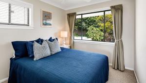 a bedroom with a blue bed and a window at The Palms Yamba - Overlooking Convent Beach in Yamba
