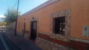a building with two windows on a street at Depto Ruta 40 Alquiler por día in Pomancillo