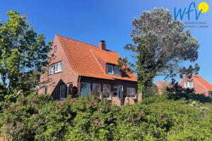 a house on a hill with trees and flowers at Ferienhaus Caterlieschen Ferienwohnung 1 in Juist