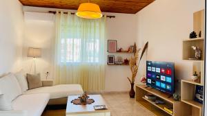 a living room with a white couch and a flat screen tv at Mia Guest House - Entire home with balcony & garden in Divjakë