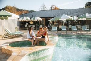 three women sitting around a pool at a resort at Hara House in Bright