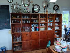 a wooden cabinet filled with dishes and plates at Folster Gardens Bed and Breakfast in Invercargill