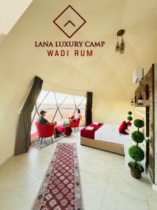 Una habitación con una cama y dos personas sentadas en sillas. en Wadi Rum Lana luxury camp, en Wadi Rum
