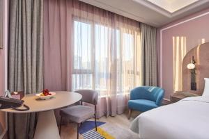 a hotel room with a bed and a table and a window at Mercure Yiwu International Trade City in Yiwu +43 photos