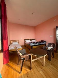 a room with two beds and a table and chairs at Sattva Retreat One Bedroom Chalets in Almora