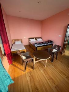 a room with a bed and a table and chairs at Sattva Retreat One Bedroom Chalets in Almora +4 photos