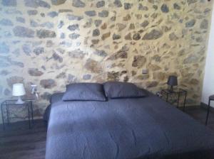 a bedroom with a stone wall with a bed at Écurie De Cucugnan in Cucugnan