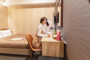 a woman sitting at a table in a hotel room at HOTEL RELIEF Kokura Station in Kitakyushu