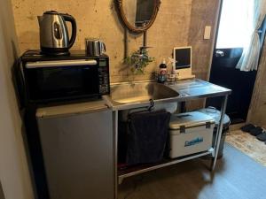 a kitchen counter with a microwave and a sink at Apple-garage in Mitoyo