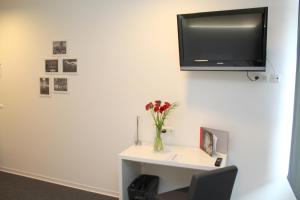 a room with a desk with a tv on the wall at mk hotel stuttgart in Stuttgart