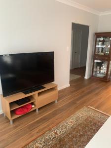 a living room with a flat screen tv on a entertainment center at Bundanoon Rochester Guest House in Bundanoon